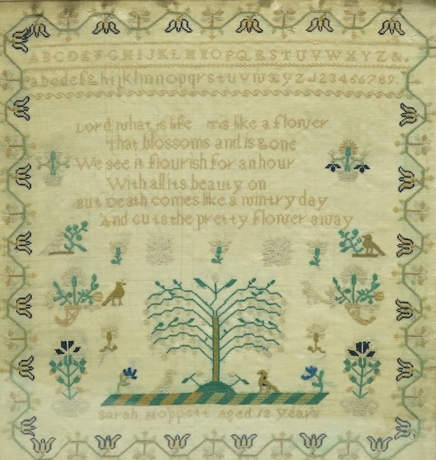 An early 19th century very finely embroidered sampler, by Sarah Hoppett aged 12 years. Embroidered with an alphabet, verse and a central panel depicting the tree of life, birds, cornucopia and flowers, within a floral vi